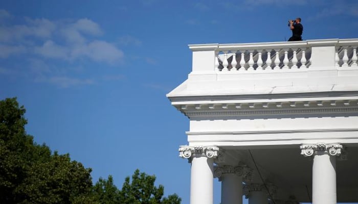 A Secret Service officer looks out from the roof of the North Portico in reaction to an apparent fence jumper at the White House in Washington, US, May 16, 2017. REUTERS/Joshua Roberts