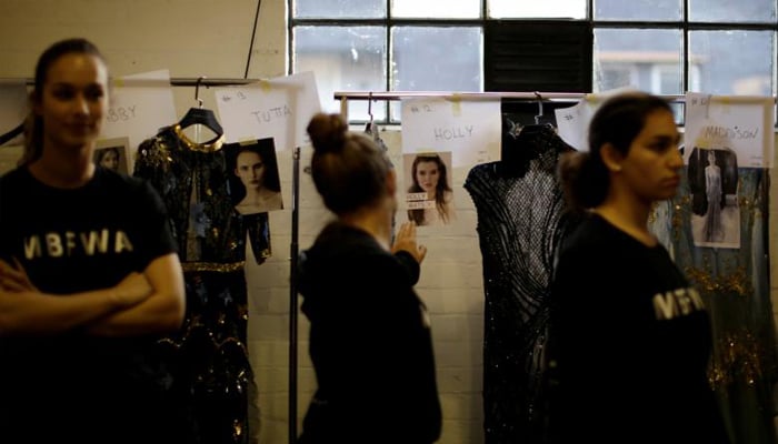 Assistants wait to help dress models, alongside their outfits and photographs, during a show by the Australian designer Steven Khalil. REUTERS/Jason Reed