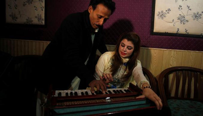 Malala Gul, a local singer learns harmonium tips from her father as she prepares to record a song at a studio in Peshawar- REUTERS