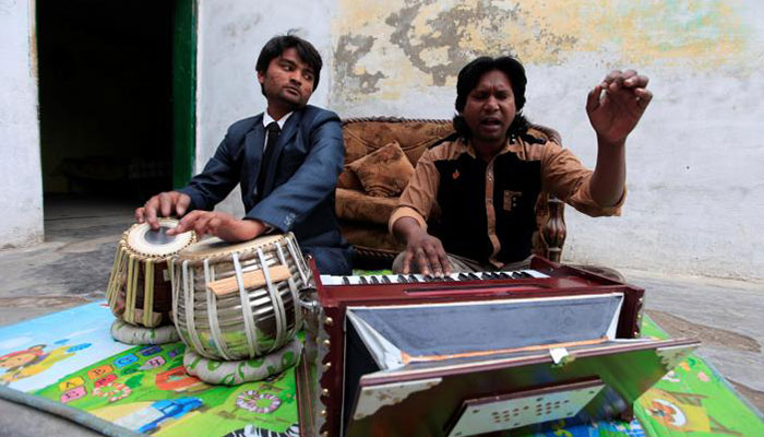 Nazar Gill, (R) a local singer, practices a song along with his brother at his residence in Rawalpindi- REUTERS