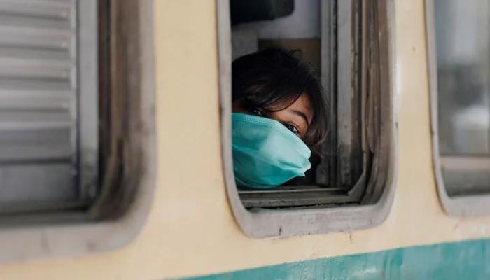 A girl wearing a protective mask looks out from a train window as she returns to her hometown, after Pakistan started easing the lockdown restrictions and allowed to resume passenger trains, following the coronavirus disease (COVID-19) outbreak, in Karachi, Pakistan. — Reuters/File