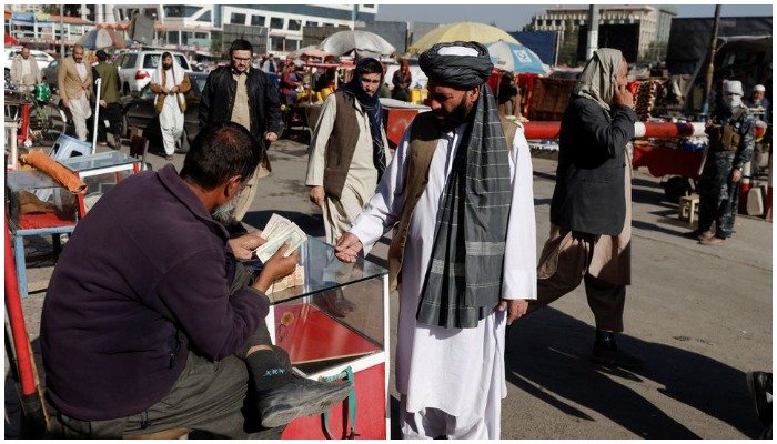 An Afghan currency exchange dealer checks banknotes in front of a man at the market in Kabul, Afghanistan October 24, 2021. — REUTERS