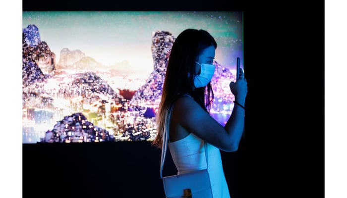 A visitor takes a photo in front of a video installation Glows in the Night by Chinese contemporary artist Yang Yongliang, which will be converted into NFTs and auctioned online at Sothebys, at the Digital Art Fair, in Hong Kong, China on September 30, 2021. — Reuters/File