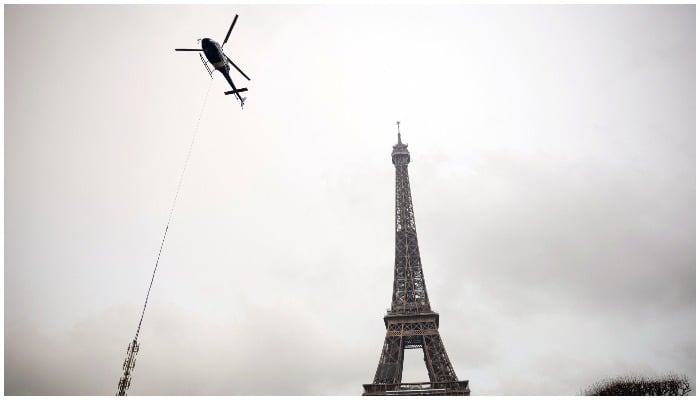 A helicopter takes off near the Eiffel Tower to install a new telecom transmission TDF (TeleDiffusion de France) antenna on its top, in Paris, France, March 15, 2022. — Reuters/Sarah Meyssonnier