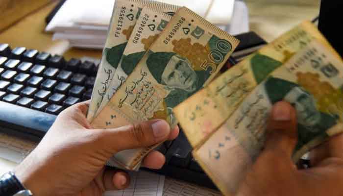 A currency dealer is counting Rs500 notes. — AFP/File