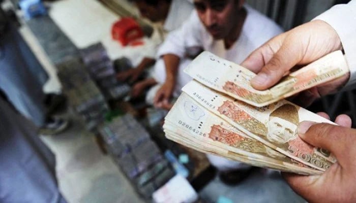 A currency dealer counts Rs5,000 notes in Pakistan in this undated photo. — AFP/File