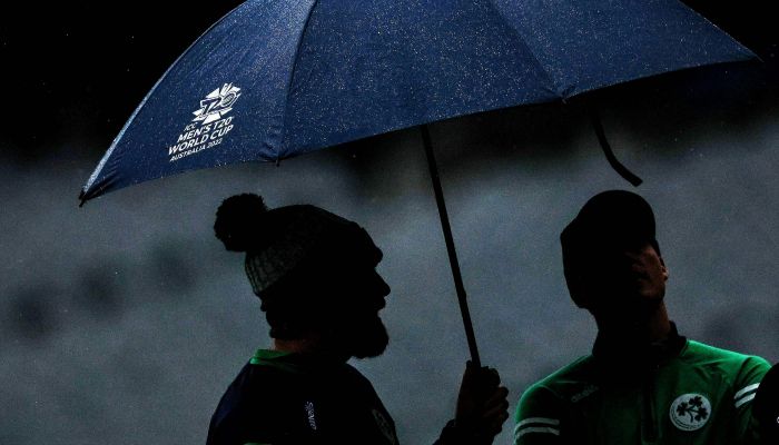 Ireland players shelter under an umbrella during the ICC men´s Twenty20 World Cup 2022 cricket match between Afghanistan and Ireland at Melbourne Cricket Ground (MCG) in Melbourne on October 28, 2022.— AFP