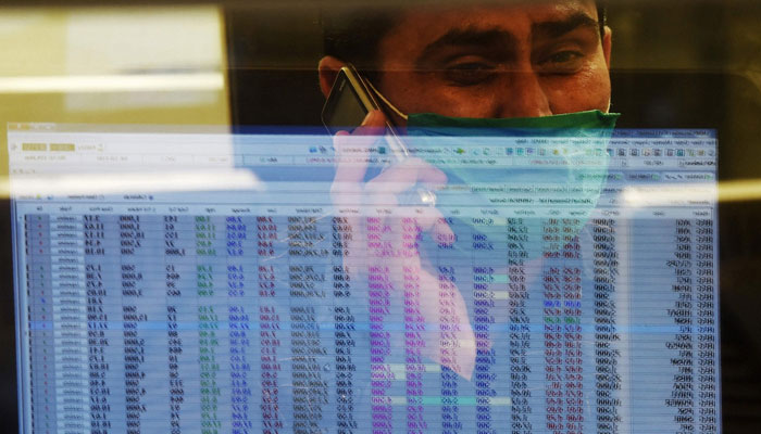 The image shows a stockbroker reading a trading screen while speaking on the phone. — Reuters/File