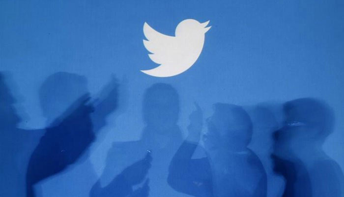 The shadows of people holding mobile phones are cast onto a backdrop projected with the Twitter logo in this illustration picture taken in Warsaw September 27, 2013. — Reuters