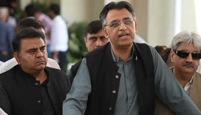 PTI secretary-general Asad Umar (c) while speaking with the media outside the Supreme Court building. —AFP/File