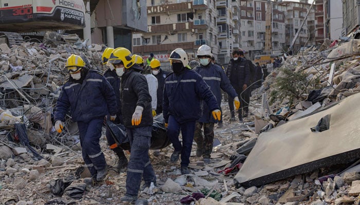 Search and rescue personnel carrying a body found under collapsed buildings in Hatay along the Mediterranean coast, southern Turkey on February 19, 2023. — AFP