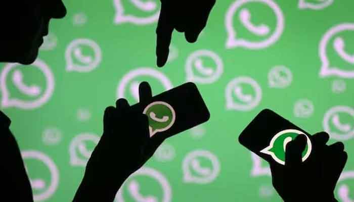 A representational image showing people holding phones with WhatsApp logo on the screen. — Reuters/File