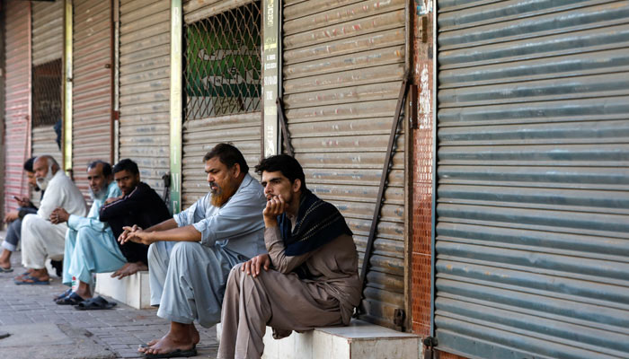 Shopkeepers and labourers sit outside closed shops during a shutter-down strike against inflation and increase in prices of petroleum products in Karachi on February 27, 2023. — Reuters