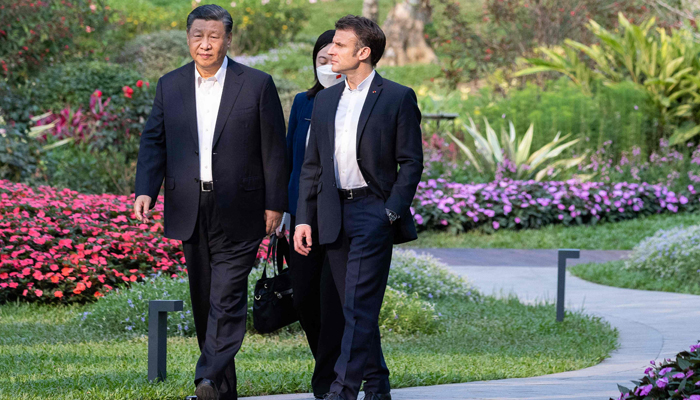 Chinese President Xi Jinping (L) and French President Emmanuel Macron speak as they visit the garden of the residence of the Governor of Guangdong, on April 7, 2023, where Chinese President XI Jinpings father, XI Zhongxun lived. — AFP