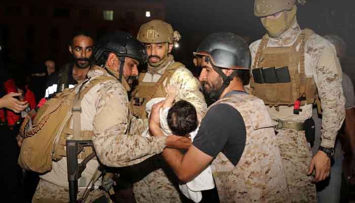 Saudi Royal Navy officers assist a child onboard their navy ship as they evacuate Saudis and other nationals are through Saudi Navy Ship from Sudan to escape the conflicts, Port Sudan, April 22, 2023. — Reuters
