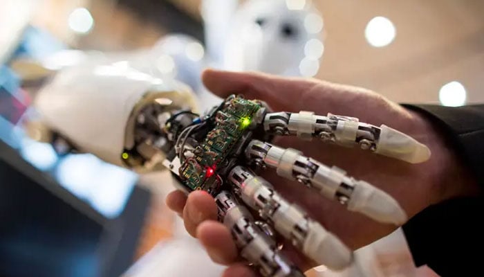 A visitor holds a hand of an AILA, or Artificial Intelligence Lightweight Android. AFP/File