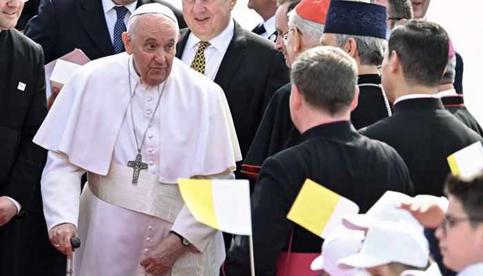 Pope Francis is greeted by children waving flags as he arrives on April 28, 2023. — AFP