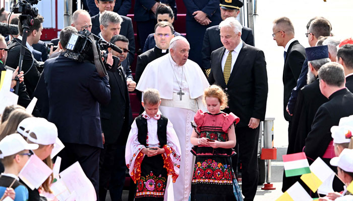 Hungarys deputy prime minister Zsolt Semjen (C-R) looks on as Pope Francis (C) is greeted by children after he arrived on April 28, 2023. — AFP