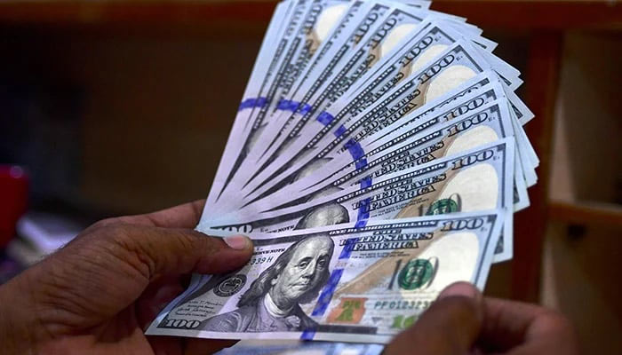 An undated image of a currency dealer counting $100 notes. — AFP