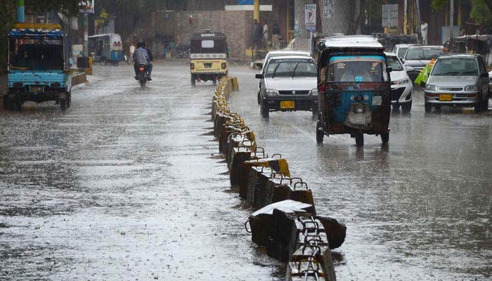 Vehicles passing through rain water during the heavy rain in Karachi on March 24, 2023. — INP