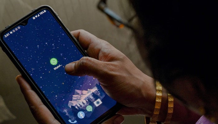 This photo illustration shows a woman checking the settings of the messaging application WhatsApp, in Bangalore. — AFP/File