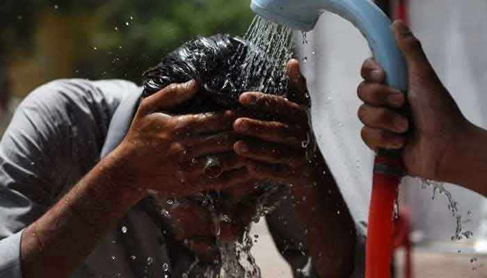 A volunteer showers a man with water during a heatwave in Karachi. — AFP/File