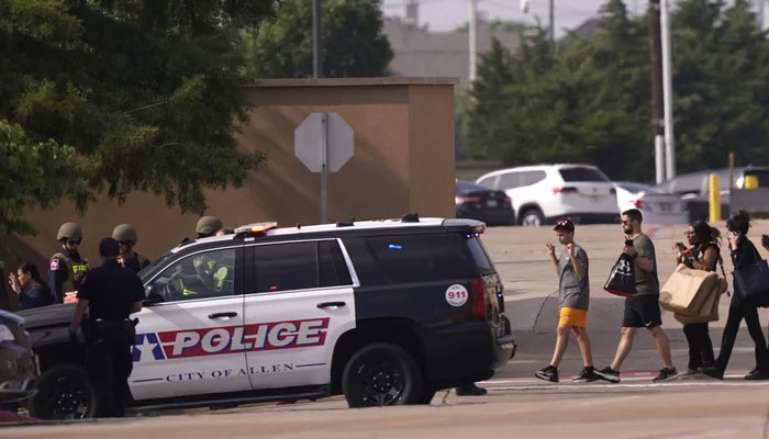 People raise their hands as they leave a shopping centre following a shooting, in Allen, Texas. —AP/file
