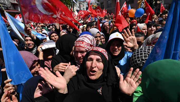 Supporters of the incumbent Turkish President, who runs for reelection, gesture and cheer as they gather for a rally in the Beyoglu district on the eve of the presidential and parliamentary elections, on the European side of Istanbul, on May 13, 2023. — AFP