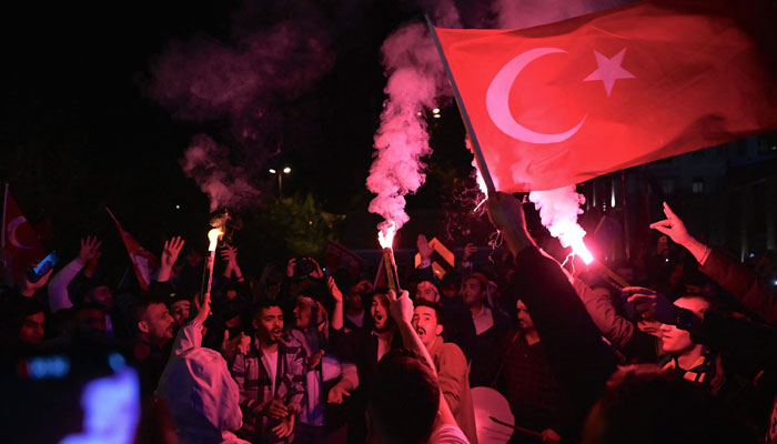 Supporters of the Turkish President light flares as they celebrate in front of the Justice and Development Party headquarters after polls closed in Turkey. — AFP