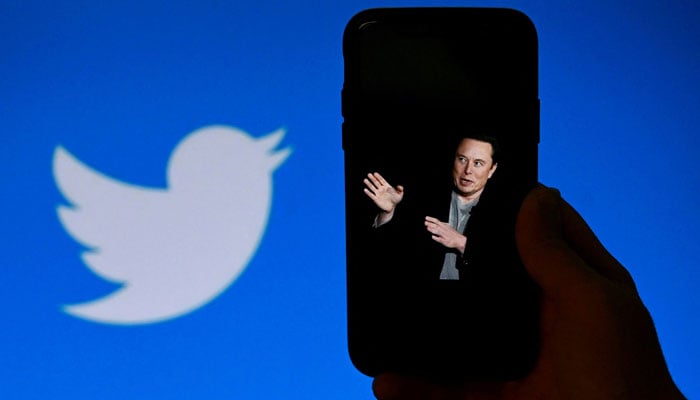 This photo shows a phone screen displaying an image of Elon Musk with the Twitter logo shown in the background, in Washington, DC. — AFP/File