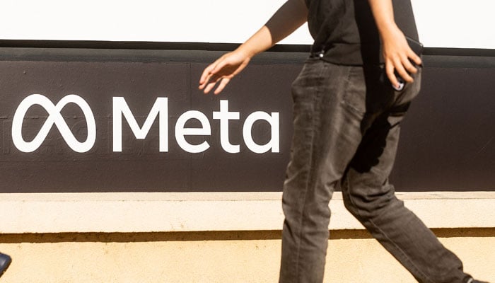 This photo shows a person walking past a newly unveiled logo for Meta,. — AFP/File