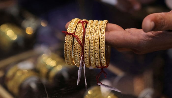 A salesperson shows gold bangles to a customer at a jewellery showroom during Dhanteras, a Hindu festival associated with Lakshmi, the goddess of wealth, in Mumbai, India, October 22, 2022.