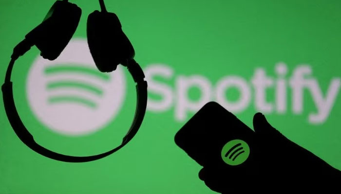 A smartphone and a headset are seen in front of a screen projection of the Spotify logo, in this picture illustration. — Reuters/File