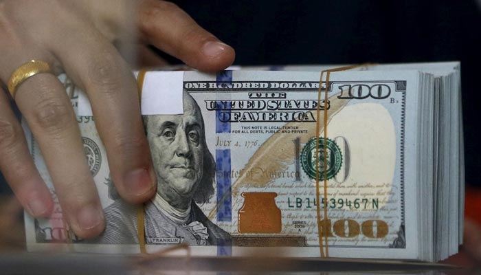 An employee of a money changer holds a stack of US dollar notes before giving it to a customer in Jakarta, October 8, 2015. — Reuters