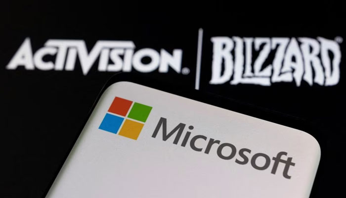 Microsoft logo is seen on a smartphone placed on displayed Activision Blizzard logo in this illustration. — Reuters