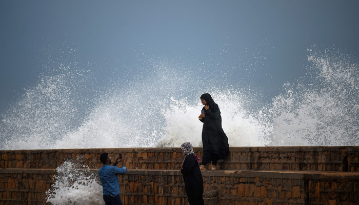 People take photos of high tides at a beach before the due onset of cyclone Biparjoy in Karachi on June 13, 2023. — AFP