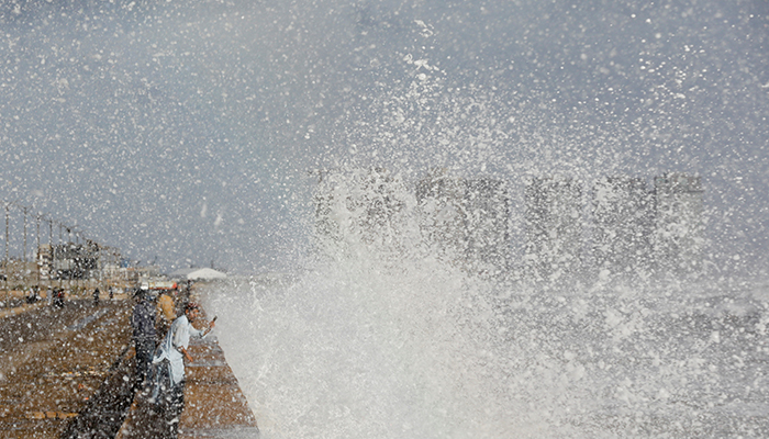 A man with a mobile phone takes a picture of rising waves, before the arrival of the cyclonic storm Biparjoy over the Arabian Sea, at Clifton beach in Karachi, June 14, 2023. — Reuters