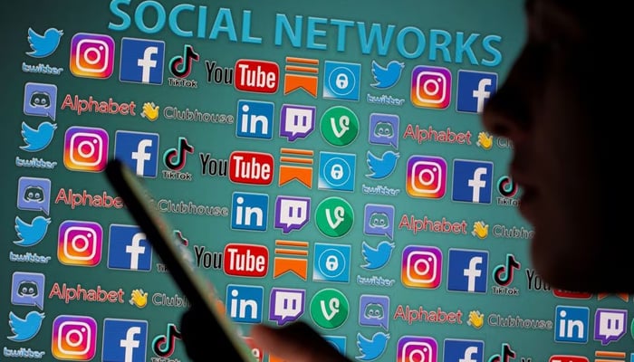 Woman with smartphone is seen in front of displayed social media logos in this illustration taken, May 25, 2021. — Reuters