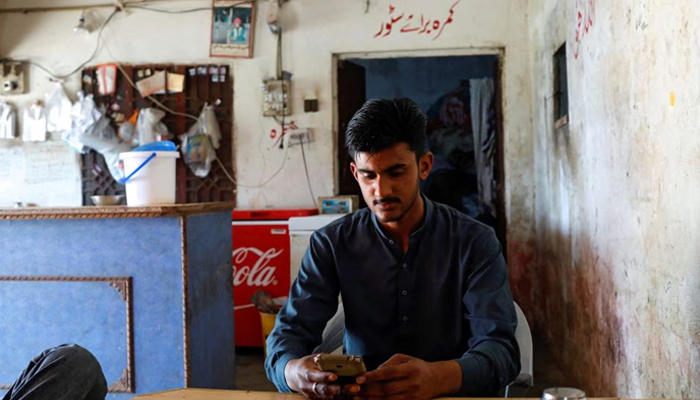 Suleman Asim, 18, friend of Muhammad Ali, 21, who along with others died when a migrant boat shipwrecked off the coast near Benghazi in Libya, looks at pictures of his friend on a mobile phone, at a tea stall in Bhojpur town in Gujrat district of Punjab province, Pakistan March 7, 2023. — Reuters