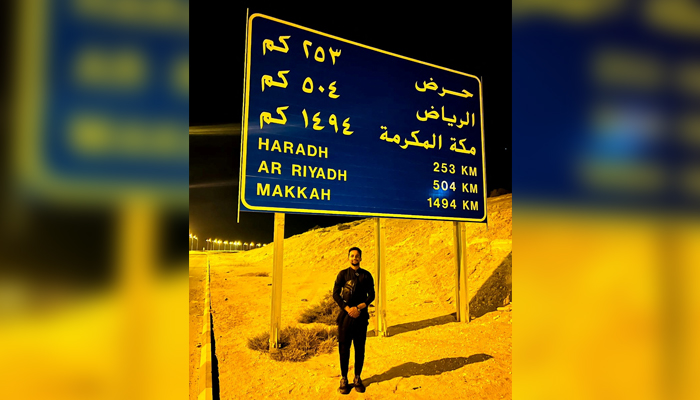 Usman Arshad is seen next to a road sign after crossing United Arab Emirates and Saudi Arabia land border in Al Batha, Saudi Arabia, in this handout photo obtained by Reuters on June 23, 2023. — Reuters