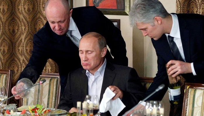 Yevgeny Prigozhin (left) assists Russian Prime Minister Vladimir Putin during a dinner with foreign scholars and journalists at the restaurant Cheval Blanc on the premises of an equestrian complex outside Moscow November 11, 2011. — Reuters