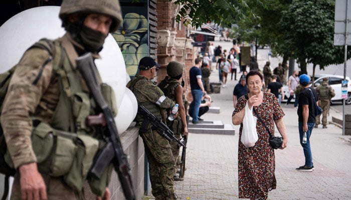 A local resident walks past members of the Wagner group in Rostov-on-Don, on June 24, 2023. — AFP