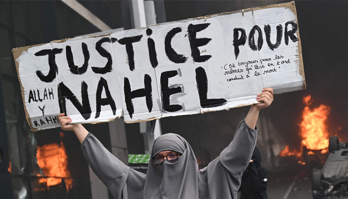 An attendee holds a banner reading Justice for Nahel in the Parisian suburb of Nanterre, on June 29, 2023. — AFP