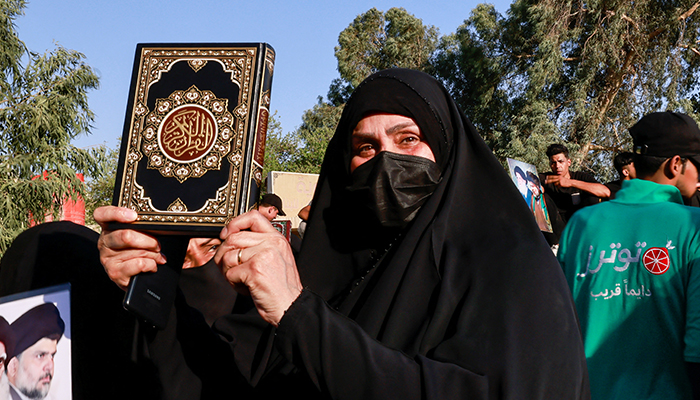 A woman holds a copy of the Quran during a protest against a man who tore up and burned a copy of the Koran outside a mosque in the Swedish capital Stockholm, near the Swedish embassy in Baghdad, Iraq, June 30, 2023. — Reuters