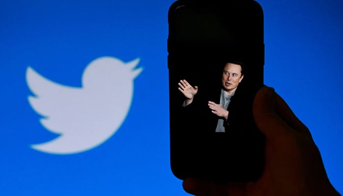 This photo shows Elon Musk on the phone screen with the Twitter logo shown in the background, on October 4, 2022, in Washington, DC. — AFP