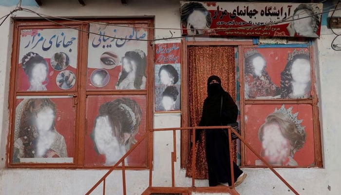 A woman wearing a niqab enters a beauty salon where the ads of women have been defaced by a shopkeeper in Kabul, Afghanistan October 6, 2021. — Reuters