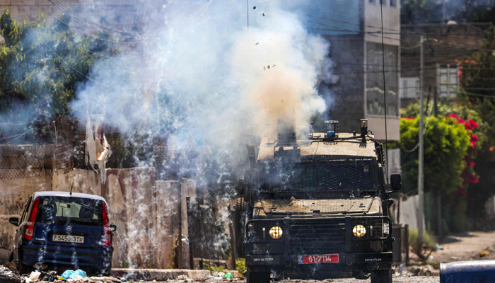 Israeli soldiers fire tear gas canisters from an armoured vehicle during an ongoing military operation in the occupied West Bank city of Jenin on July 4, 2023. — AFP