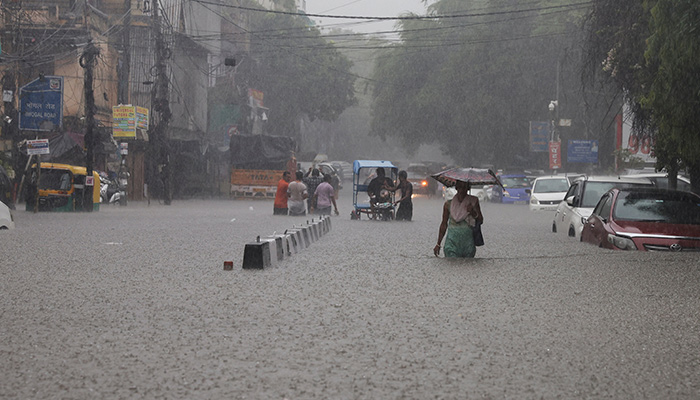 People wade through a flooded street after heavy rains in New Delhi, India, July 8, 2023.