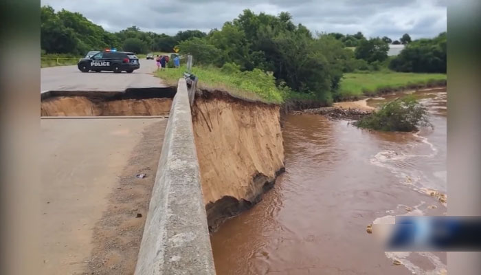 This image shows police vehicle standing on the other side of the road after the Oklahoma City bridge washed out due to severe storms on July 8, 2023. Screengrab/YouTube/KOCO 5 News