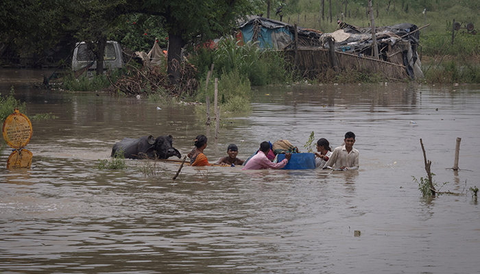 Residents carry their belongings through a field flooded with the rising water level of river Yamuna after heavy monsoon rains in New Delhi, India, July 11, 2023. — Reuters